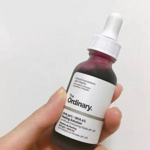 لقطة قريبة لعبوة سيروم الأحماض بشعار The Ordinary في يد
