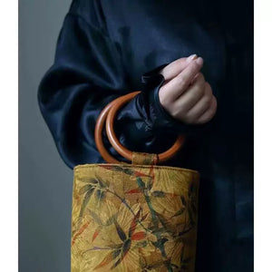 حقيبة يد Bucket Bag بتصميم خشبي دائري ولون خردلي مميز.