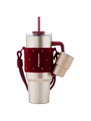 كوب Tumbler من Starbucks ذهبي مع حامل أحمر فاخر.
