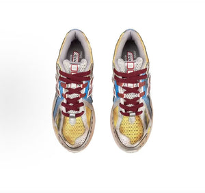 Top-down aerial shot of a pair of custom cell-shaded New Balance shoes, displaying vibrant yellow toe box mesh, blue side overlays, maroon laces, and cell-shaded comic line details.
