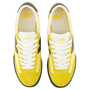 Top-down aerial view of a pair of yellow and black New Balance RC30 shoes, displaying bright yellow suede toe caps and eyestays, light yellow nylon vamps, crisp white laces, off-white nylon tongues with yellow NB logo tags, and cream-colored insoles featuring yellow printed branding.