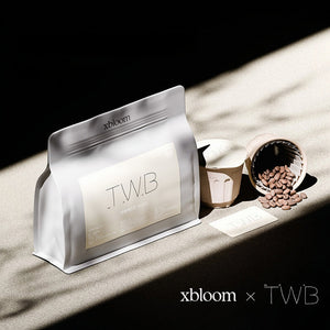 A promotional image showing a TWB coffee bag and XBloom xpods coffee capsules on a wooden surface with a dark shadow background, showcasing the 'xbloom x TWB' collaboration text.