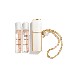 Top view of CHANEL Coco Mademoiselle travel set with two 7ml perfume refill vials alongside a luxury white and gold spray case attached to a golden jewelry chain on a white background.