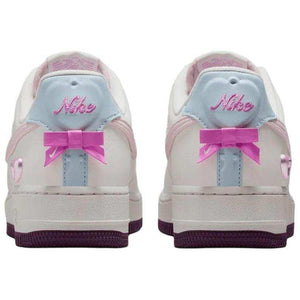 حذاء Nike Air Force 1 أبيض مزين بفيونكة وقلب وردي.