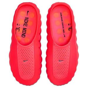 Top-down view of the Nike Mind 001 shoes in neon red, showing the branded footbed inserts and bright orange massage pods inside.