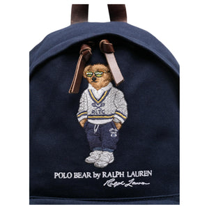 Close-up of the iconic embroidered Polo Bear wearing a sweater and glasses on an original navy Ralph Lauren backpack with brown leather zipper pulls.
لقطة قريبة لتطريز دب بولو الشهير الذي يرتدي سترة ونظارات على حقيبة ظهر رالف لورين أصلية باللون الكحلي مع أشرطة سحاب جلدية بنية.