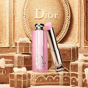 عطر ديور الوردي وبلسم الشفاه الفضي على خلفية ذهبية بيضاوية
