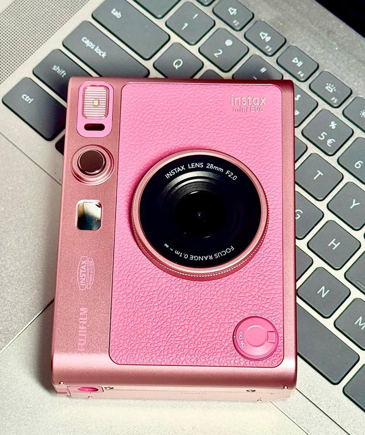 كاميرا فورية هايبرد FUJIFILM Instax Mini Evo وردية على كمبيوتر محمول.