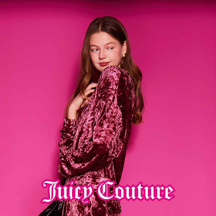 Juicy Couture luxurious velvet blouse with embroidered logo on pink background.