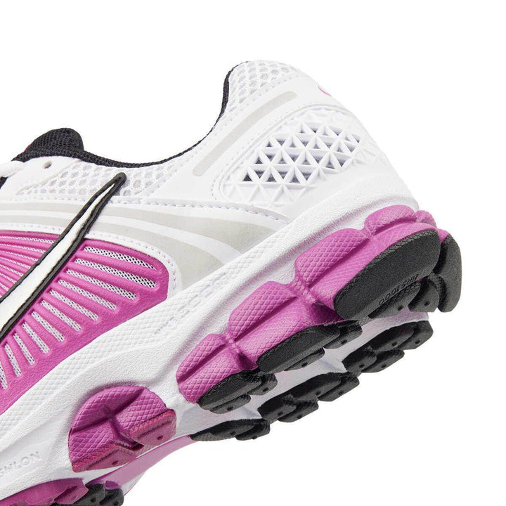 White and pink Nike Zoom Vomero 5 athletic shoe with mesh design and rubber sole.