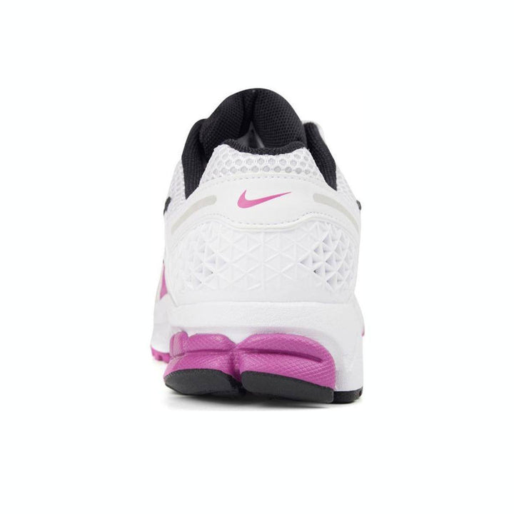 White Nike Zoom Vomero 5 sneaker with pink accents, mesh design, and sturdy rubber sole.