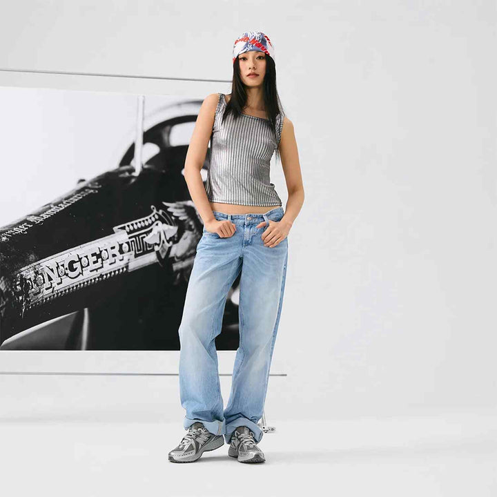 Woman wearing New Balance 1906R metallic silver sneakers with casual outfit and bandana against white background