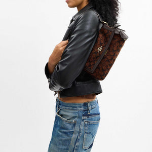 حقيبة كتف COACH بنقشة Signature المميزة باللون البني.