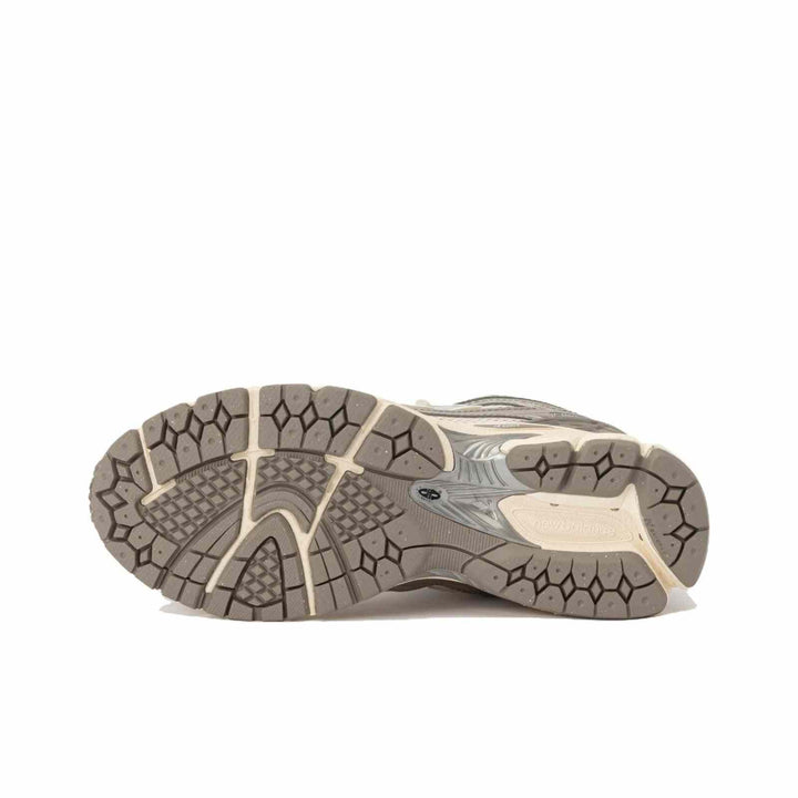 Outsole view of New Balance 1906R beige sneaker with silver accents and durable tread pattern