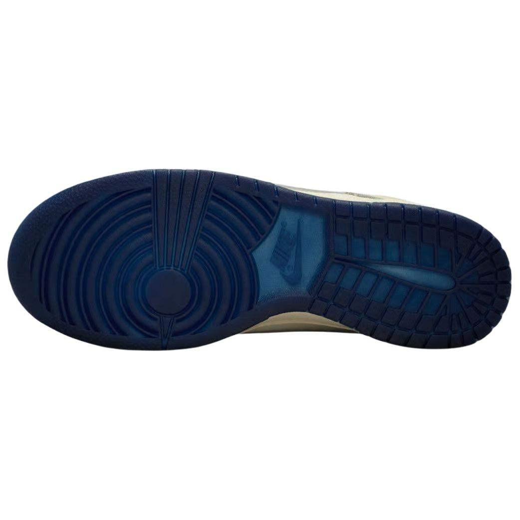 حذاء Nike Dunk Low بتفاصيل عاكسة للضوء لون كريمي.