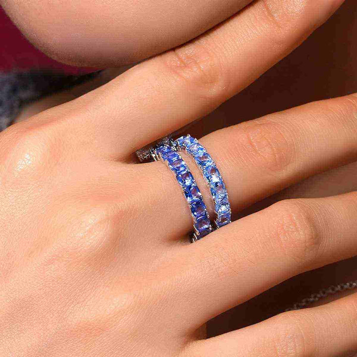 APM Monaco blue sparkle ring with square stones in a circular design on a hand, luxurious and elegant accessory.