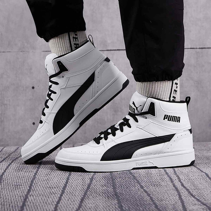 Puma high-top sneakers in white and black with durable material and rubber sole for ankle support and stability, perfect for sporty fashion.