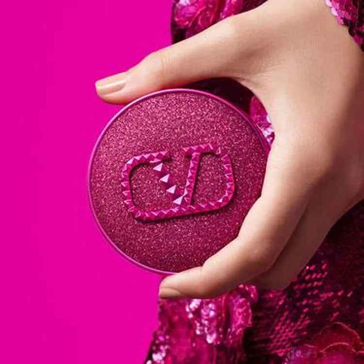Hand holding Valentino Beauty Fantasy Pink foundation compact with sparkling pink design against vibrant pink background