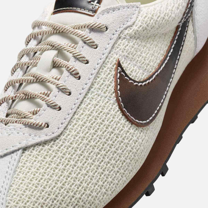Close-up of Nike LD-1000 sneaker featuring woven upper, leather swoosh, and waffle-pattern sole in soft pearl, black, and fauna brown colors