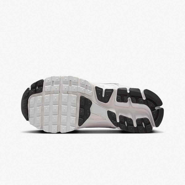 Bottom view of Nike Vomero 5 kids sneakers with durable rubber sole and grip pattern in white and black.