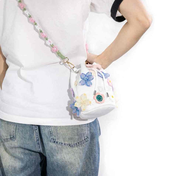 شنطة Dior مزينة بتصميم دلو أبيض مع تطريز زهور ثلاثية الأبعاد وحزام كروشيه ملون.
