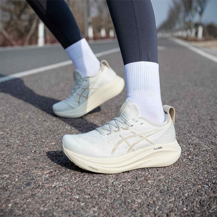 ASICS Gel-Nimbus 27 beige running shoes on pavement for comfort and performance.