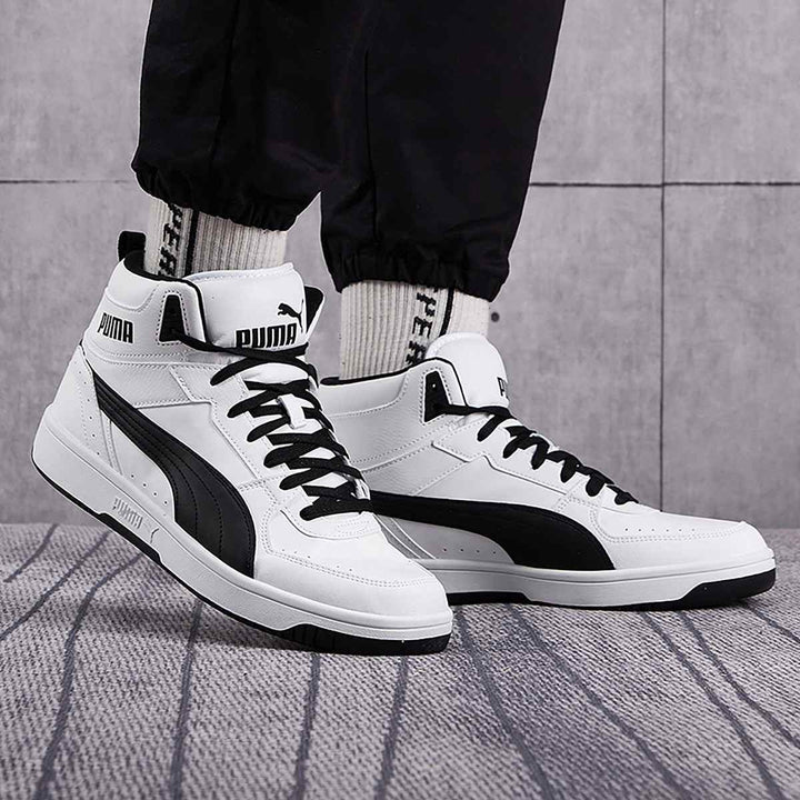 High-top Puma sneakers in classic white and black design, offering ankle support with a durable build and rubber sole for stability.