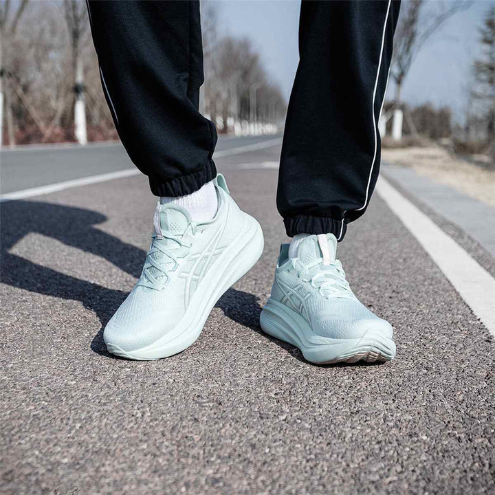 ASICS Gel-Nimbus 27 in light green, lightweight and stylish running shoes on a road.