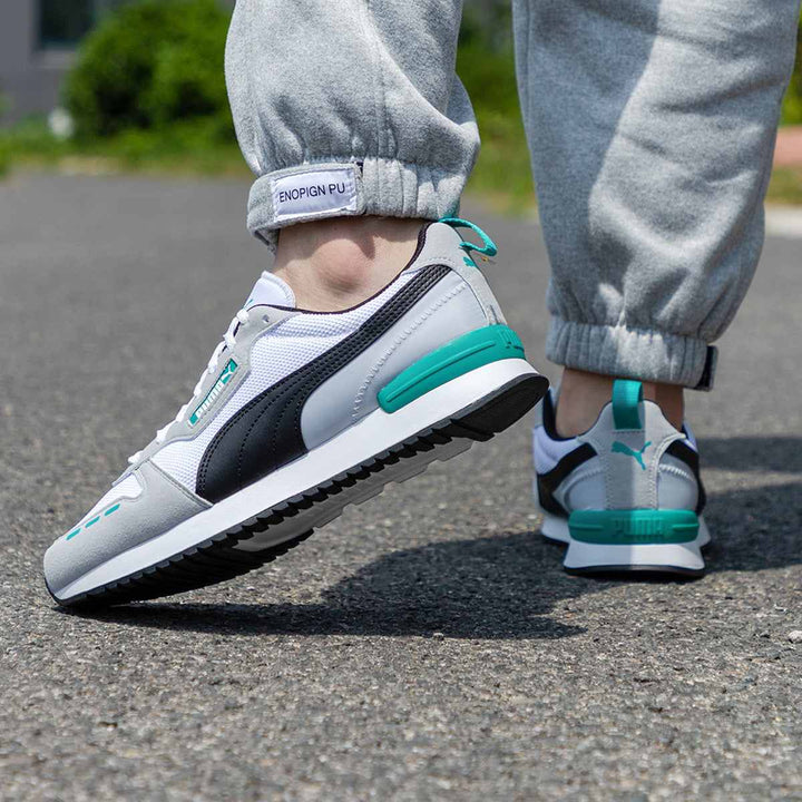 Puma retro sneaker in white, black, and mint green, featuring mesh and synthetic leather details, worn outdoors.