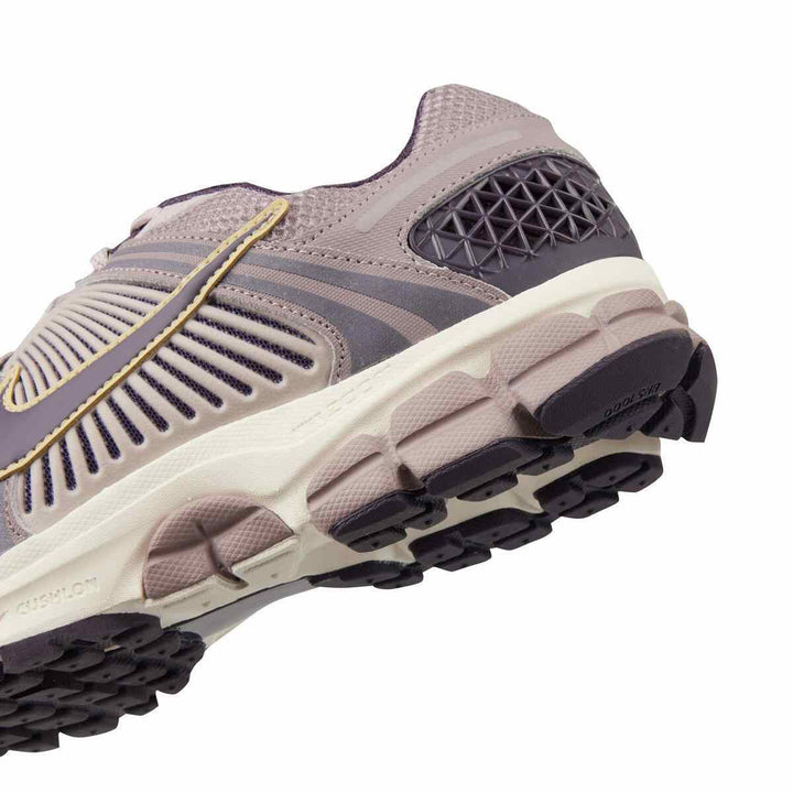 Nike ZOOM VOMERO 5 sneaker in lavender with gold accents, featuring a durable rubber sole and breathable mesh design.