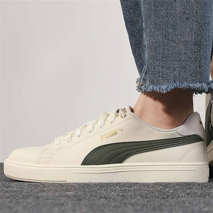 Puma ivory sneakers with olive side stripe and gold logo, worn with jeans.