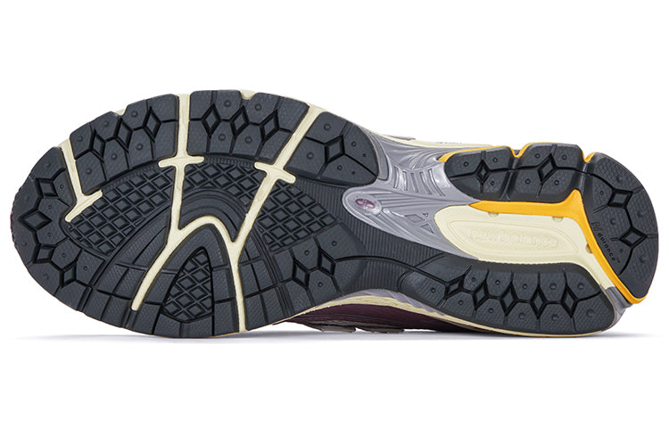 Bottom outsole view of grey and purple New Balance shoes 1906R model, featuring dark grey rubber traction tread pattern, cream flex grooves, bright orange heel highlights, and a grey midfoot Stability Web arch support shank.