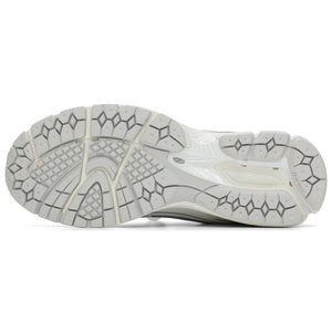 Bottom outsole view of grey and white New Balance shoes 1906R model, featuring a light grey rubber traction tread pattern, off-white flex grooves, and a white midfoot Stability Web arch support shank.