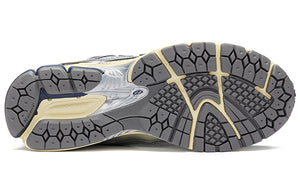 Bottom outsole view of metallic silver and navy blue New Balance shoes 1906R model, featuring dark grey rubber traction tread pattern, cream flex grooves, navy blue heel accents, and a silver midfoot Stability Web arch support shank.