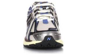 Front toe-on view of white, blue, and purple New Balance shoes 1906R model, displaying breathable white mesh toe box with metallic silver and navy overlays, blue tongue accents, white laces, and black rubber toe cap featuring the blue N logo.