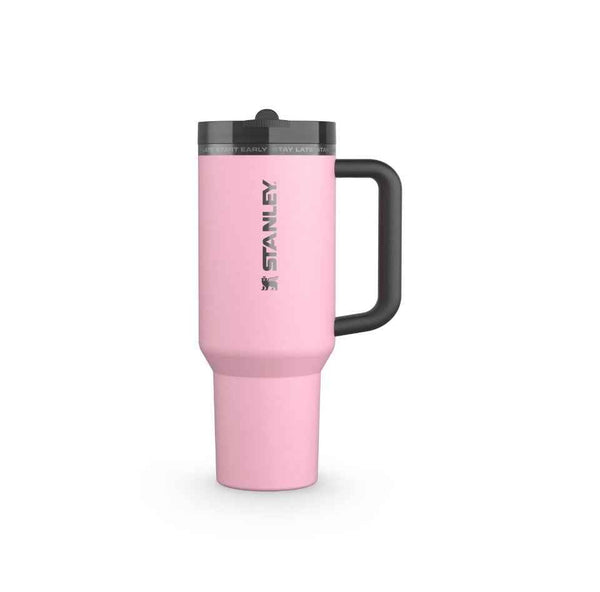 ستانلي ميسي Pink Stanley thermal travel mug with black handle and lid, branded with Stanley logo, designed for hot and cold drinks.