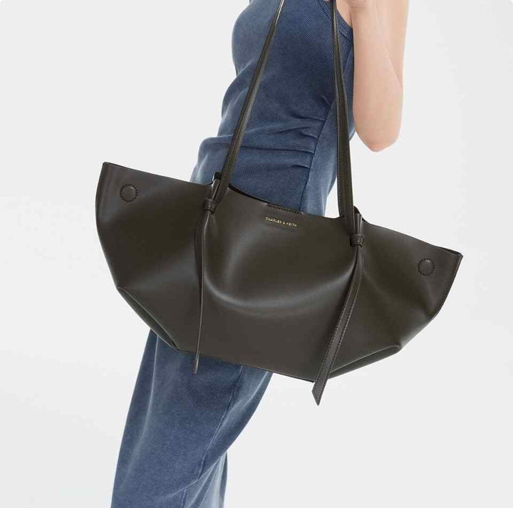 CHARLES&KEITH black reversible tote bag with soft leather and long shoulder straps, worn by a model in a blue dress