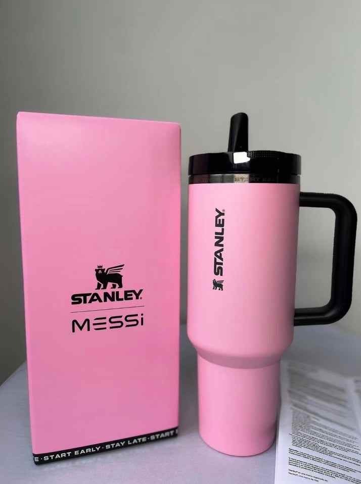 pink Stanley Messi thermal cup with black handle and lid next to matching pink box