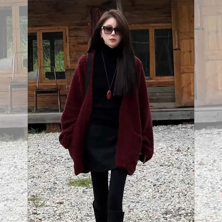 woman wearing burgundy long wide winter cardigan with pockets over all-black outfit outdoors