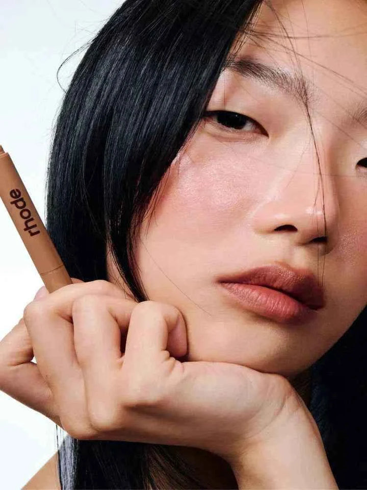 Woman holding Rhode Lip Liner lip pencil with smooth, natural makeup look