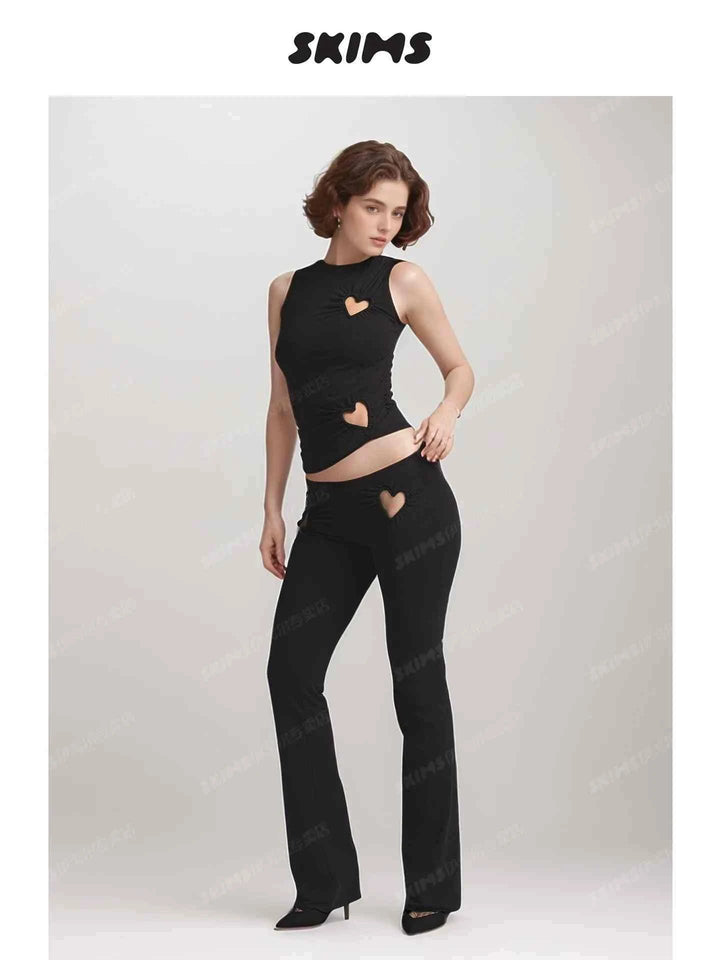 SKIMS Kardashian women's black sleeveless top and pants set with heart-shaped cutouts on chest, waist, and hip.