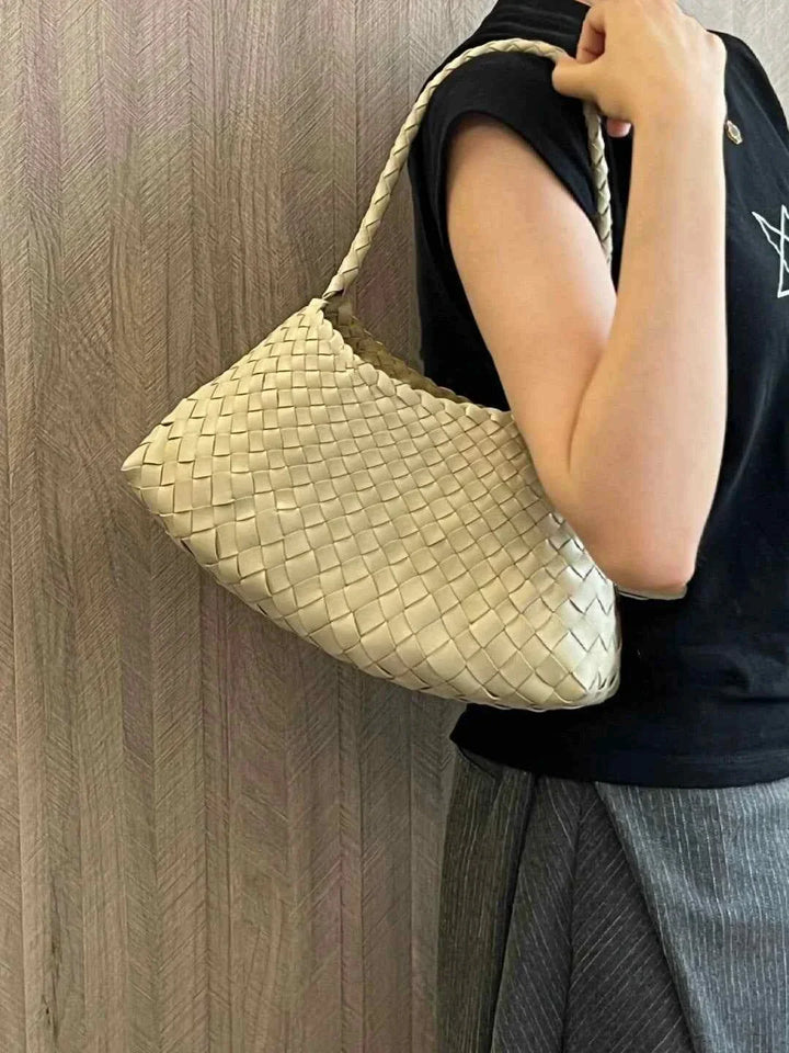Beige dragon woven bag made of braided natural leather held by a person over the shoulder