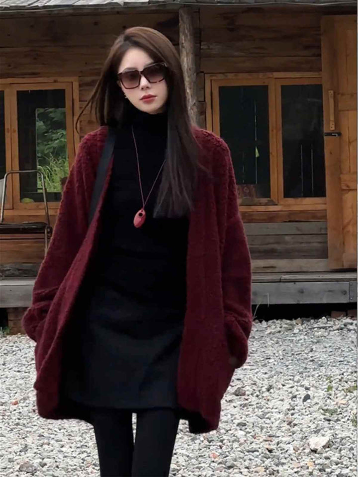 woman wearing long burgundy winter cardigan with black dress and sunglasses outdoors