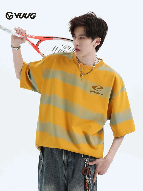 Man wearing oversized Ice Silk t-shirt with yellow and gray stripes holding a tennis racket