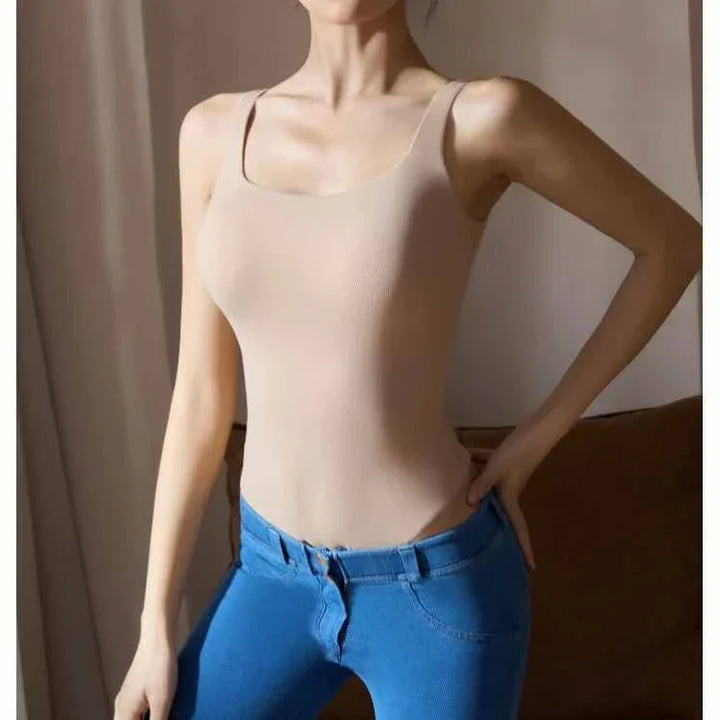 woman wearing beige seamless scoop neck thong bodysuit with blue jeans standing indoors
