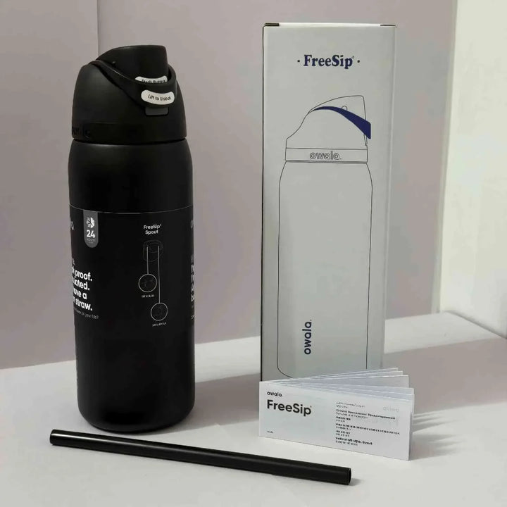Owala FreeSip black insulated water bottle with dual drinking spout, packaging box, and black reusable straw
