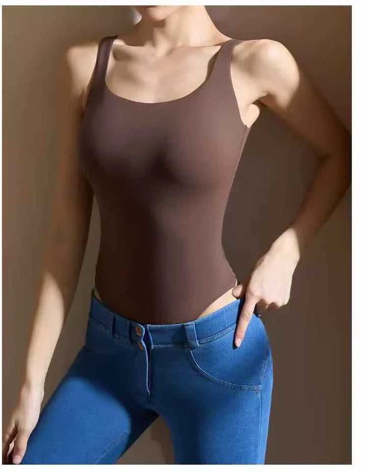 brown seamless SKIMS Kardashian بودي سكوب ثونغ bodysuit with scoop neck and thong back worn with blue jeans