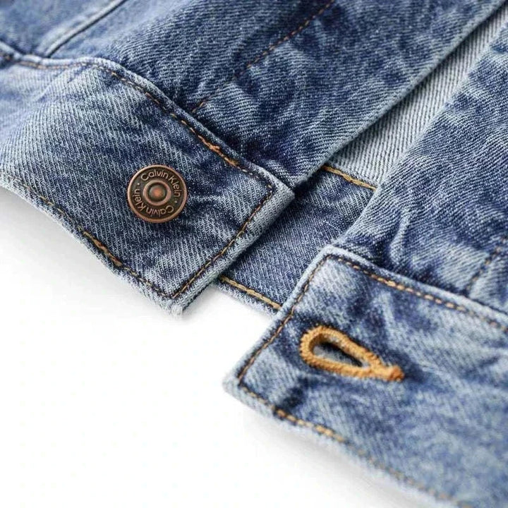 جاكيت جينز واسع من CALVIN KLEIN بتفاصيل برونزية وخياطة متباينة بلون أزرق متدرج