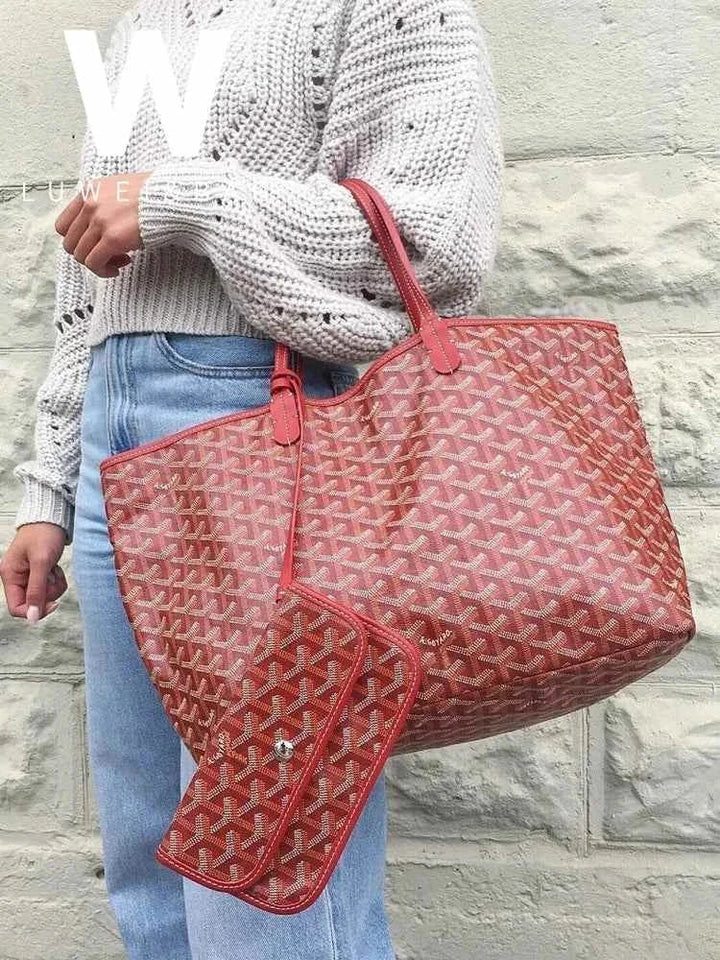 red geometric patterned hobo bag حقيبة كتف with leather strap and matching pouch held by person in knit sweater and jeans