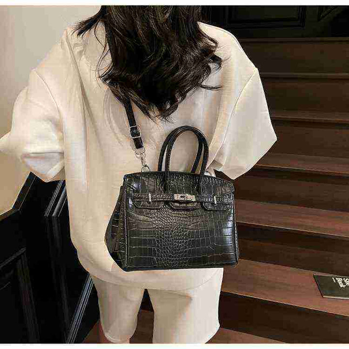 Black Birkin-style women's handbag with crocodile pattern and crossbody strap, made of high-quality leather.